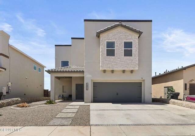 view of front facade featuring a tiled roof, driveway, a garage, stone siding, and stucco siding