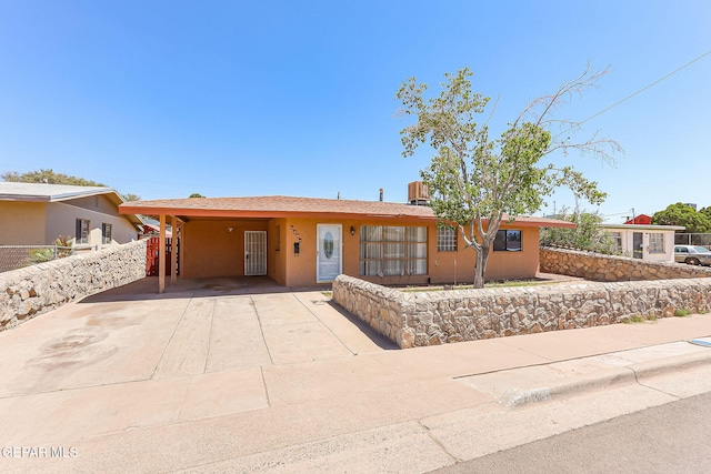 ranch-style house with concrete driveway, fence, stucco siding, and an attached carport