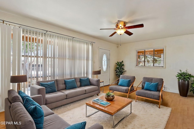 living room with a ceiling fan, baseboards, and wood finished floors