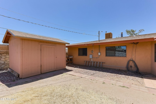 rear view of property featuring an outbuilding, a patio area, and a storage shed
