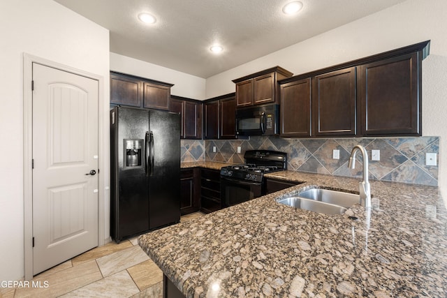kitchen with dark brown cabinets, a sink, dark stone countertops, tasteful backsplash, and black appliances