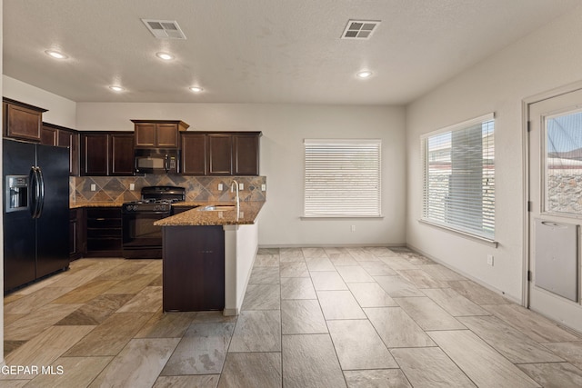 kitchen featuring visible vents, a sink, a peninsula, and black appliances