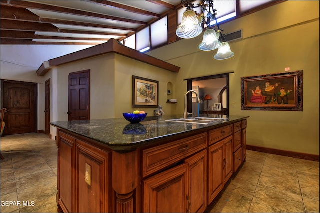 5401 Tierra Vista Dr, El Paso, TX 79932 - kitchen featuring a sink, baseboards, light stone finish floors, a center island with sink, and brown cabinetry