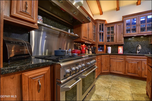 5401 Tierra Vista Dr, El Paso, TX 79932 - kitchen with range with two ovens, a sink, backsplash, exhaust hood, and glass insert cabinets