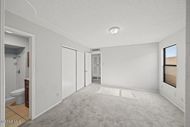 4808 Sagittarius Ave, El Paso, TX 79924 - unfurnished bedroom with a textured ceiling, visible vents, carpet floors, a closet, and ensuite bathroom