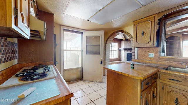 6001 Canton Ct, El Paso, TX 79905 - kitchen with brown cabinetry, a sink, light tile patterned floors, and white cooktop