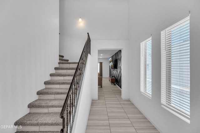 stairway featuring baseboards, tile patterned floors, and a healthy amount of sunlight