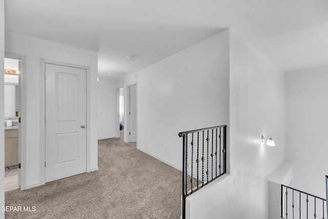 hallway featuring baseboards, carpet flooring, and an upstairs landing