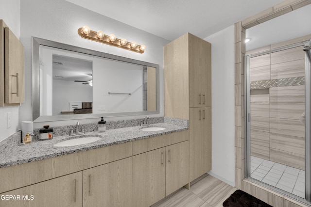 full bath with a sink, a ceiling fan, and a stall shower