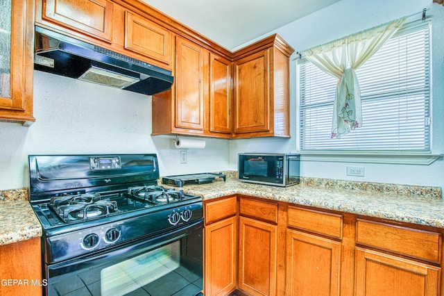 14253 Hacienda Rock Dr, El Paso, TX 79938 - kitchen featuring black range with gas stovetop, under cabinet range hood, brown cabinets, light stone countertops, and tile patterned floors