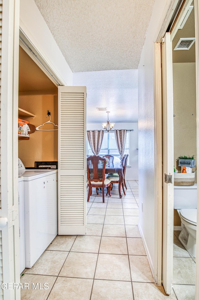 14253 Hacienda Rock Dr, El Paso, TX 79938 - hall featuring a textured ceiling, light tile patterned floors, a chandelier, and separate washer and dryer