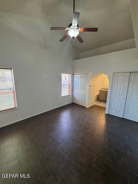 interior space with arched walkways, high vaulted ceiling, and dark wood-type flooring