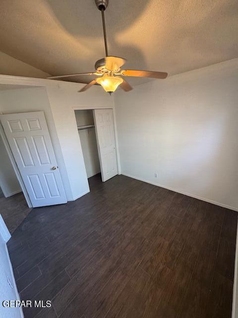 unfurnished bedroom with a closet, baseboards, ceiling fan, a textured ceiling, and dark wood finished floors