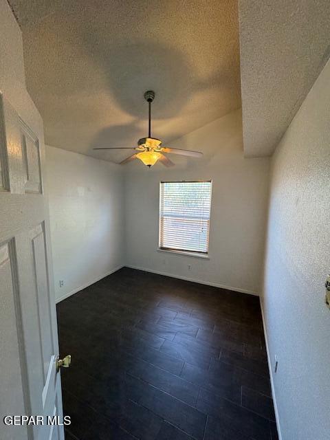 empty room featuring baseboards, a textured ceiling, ceiling fan, and dark wood-style flooring