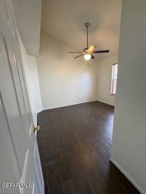 unfurnished room with baseboards, a ceiling fan, and dark wood-style flooring