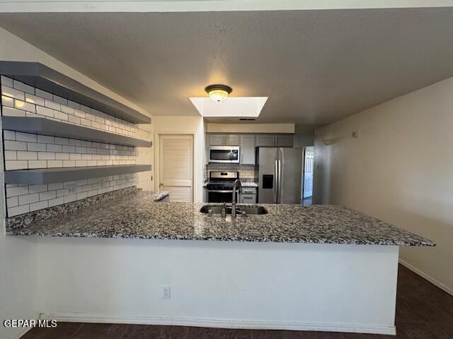 kitchen featuring backsplash, stainless steel appliances, a sink, and dark stone counters