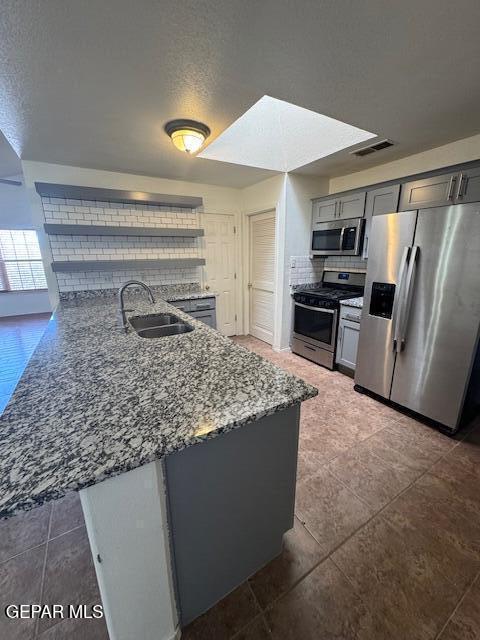 kitchen featuring a sink, visible vents, stainless steel appliances, stone counters, and gray cabinetry