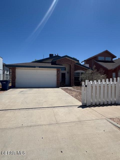view of front of house with fence, an attached garage, driveway, and brick siding