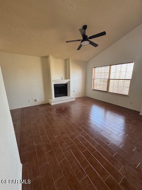 unfurnished living room with vaulted ceiling, a fireplace, a ceiling fan, and dark wood-style floors