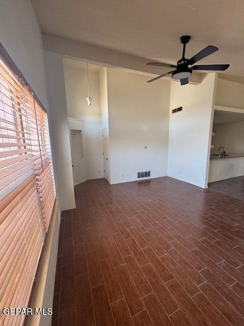 unfurnished room featuring ceiling fan, dark wood-style floors, and visible vents