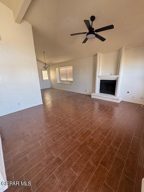unfurnished living room featuring a brick fireplace, dark wood-style flooring, and ceiling fan