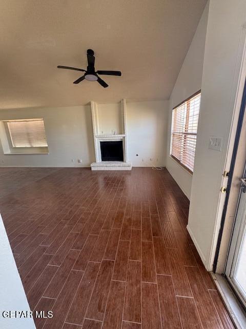 unfurnished living room with dark wood-style flooring, ceiling fan, and a fireplace