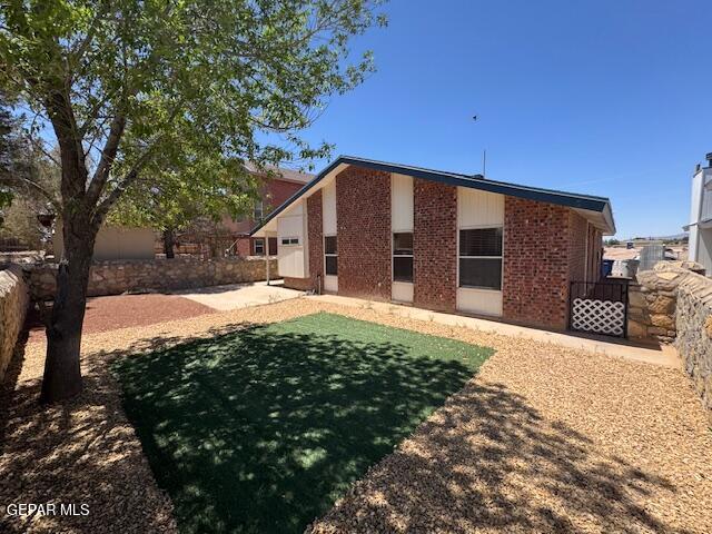 back of property featuring fence, a patio area, and brick siding