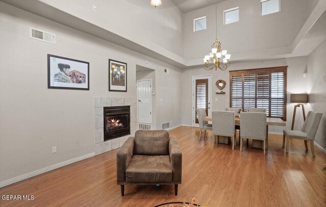 12164 Sitting Bull Dr, El Paso, TX 79936 - dining area with wood finished floors, baseboards, a chandelier, a tiled fireplace, and a towering ceiling