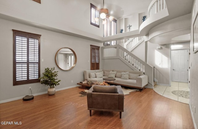 12164 Sitting Bull Dr, El Paso, TX 79936 - living area with wood finished floors, stairway, baseboards, a ceiling fan, and a towering ceiling