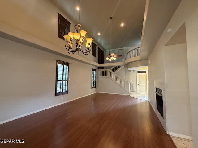 12164 Sitting Bull Dr, El Paso, TX 79936 - unfurnished living room featuring a high ceiling, wood finished floors, a chandelier, stairs, and a fireplace