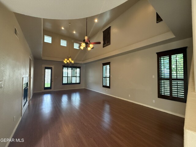 12164 Sitting Bull Dr, El Paso, TX 79936 - unfurnished living room featuring wood finished floors, ceiling fan, healthy amount of natural light, baseboards, and a high ceiling