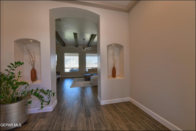 hallway with baseboards, dark wood-style floors, beam ceiling, and arched walkways
