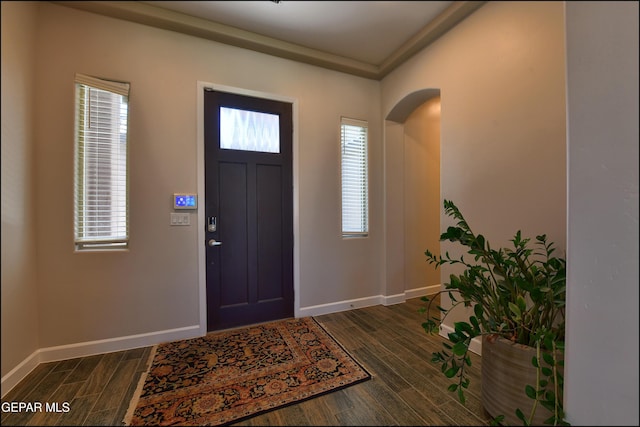 entryway with arched walkways, baseboards, and dark wood-style floors
