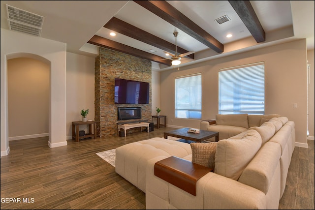 living area featuring visible vents, arched walkways, baseboards, and beamed ceiling
