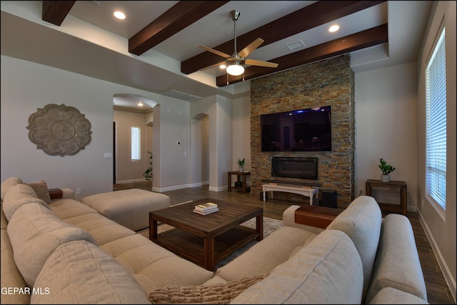 living area featuring arched walkways, beamed ceiling, a ceiling fan, and wood finished floors