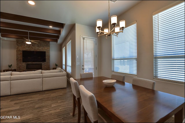 dining area featuring ceiling fan with notable chandelier, dark wood-style floors, beam ceiling, and a wealth of natural light