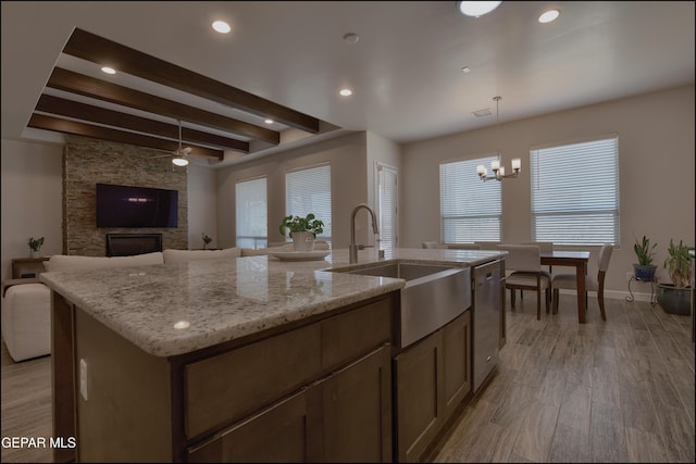 kitchen featuring beam ceiling, a sink, open floor plan, stainless steel dishwasher, and a center island with sink