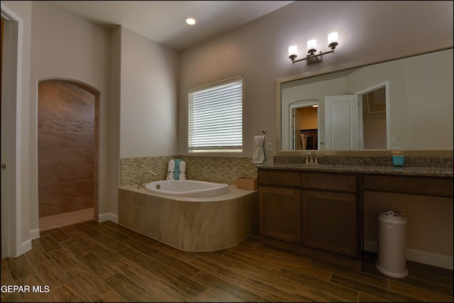 full bath featuring wood tiled floor, a bath, vanity, recessed lighting, and tiled shower