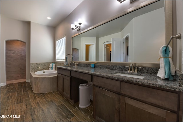 bathroom featuring double vanity, a sink, a garden tub, and wood finish floors