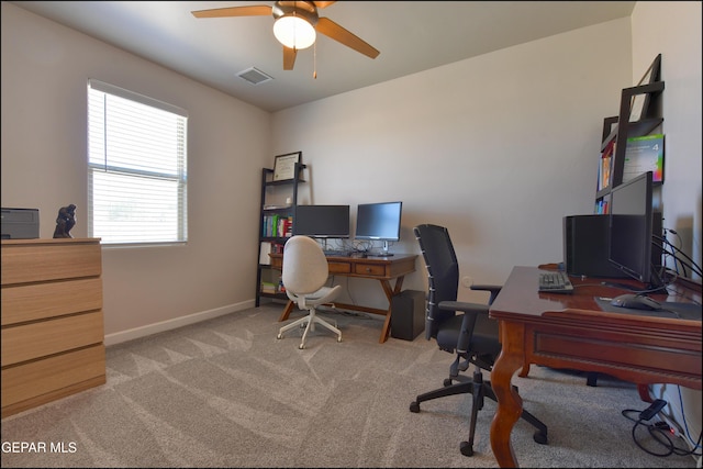 office space featuring light colored carpet, ceiling fan, visible vents, and baseboards
