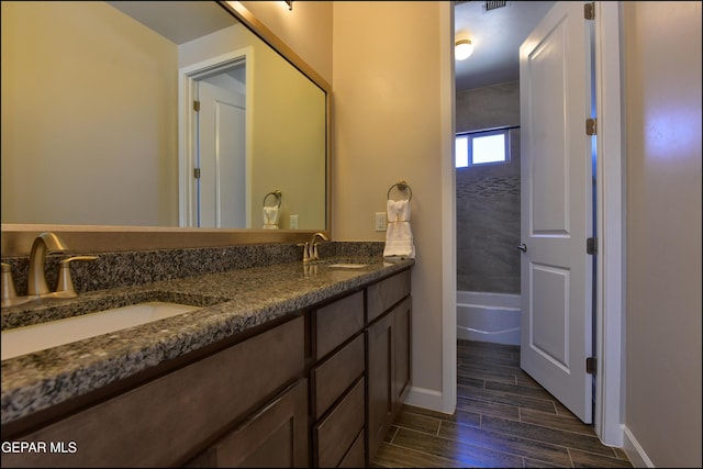 bathroom with double vanity, baseboards, a sink, and wood finished floors