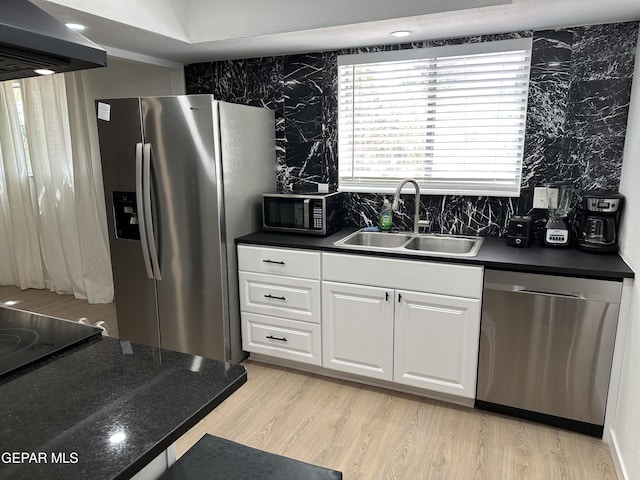 kitchen with dark countertops, extractor fan, white cabinetry, a sink, and stainless steel appliances