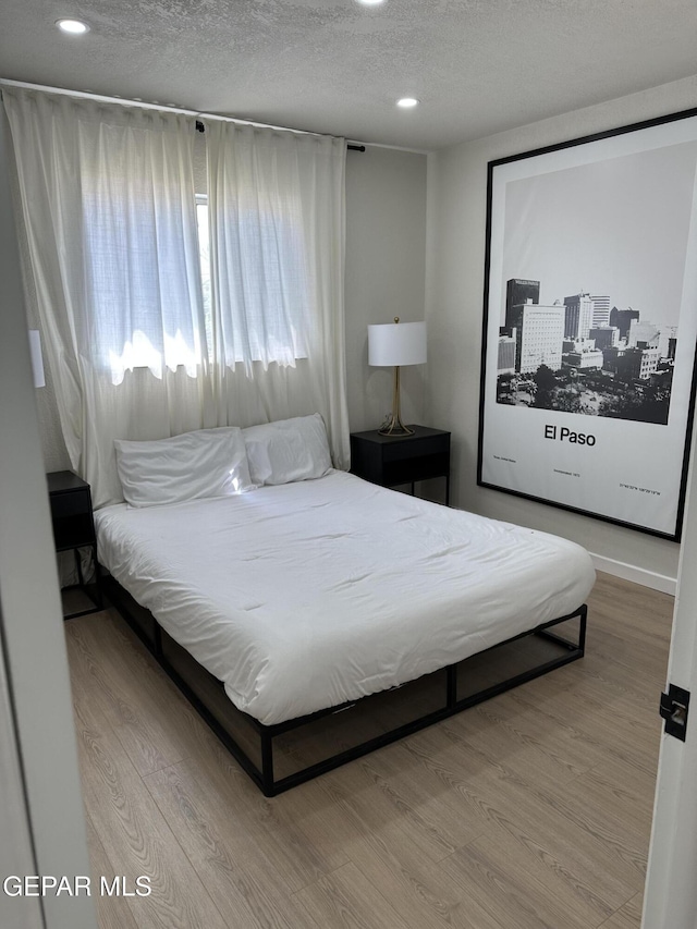 bedroom featuring a textured ceiling, recessed lighting, and wood finished floors