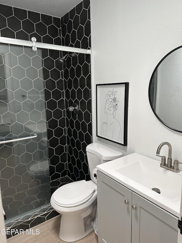 full bath with toilet, a shower stall, wood finished floors, and vanity