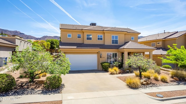 traditional-style house featuring a garage, stucco siding, concrete driveway, a mountain view, and a tile roof