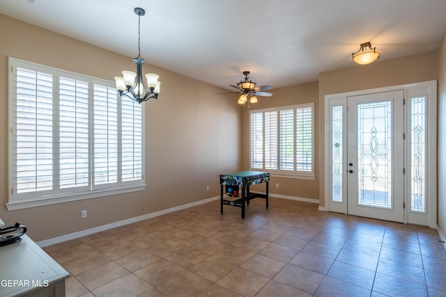 unfurnished dining area featuring light tile patterned flooring, baseboards, and ceiling fan with notable chandelier