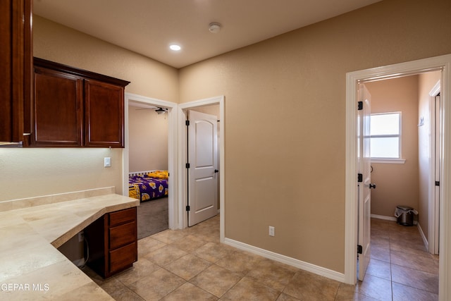 interior space featuring light countertops, baseboards, dark brown cabinetry, and light tile patterned floors