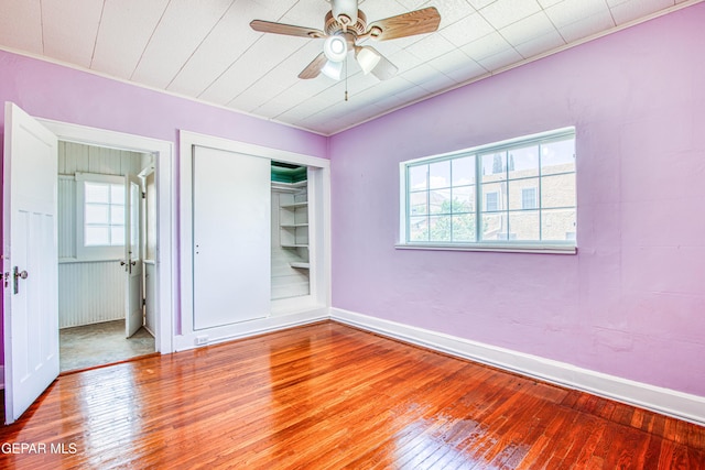 unfurnished bedroom with ceiling fan, a closet, hardwood / wood-style floors, and baseboards