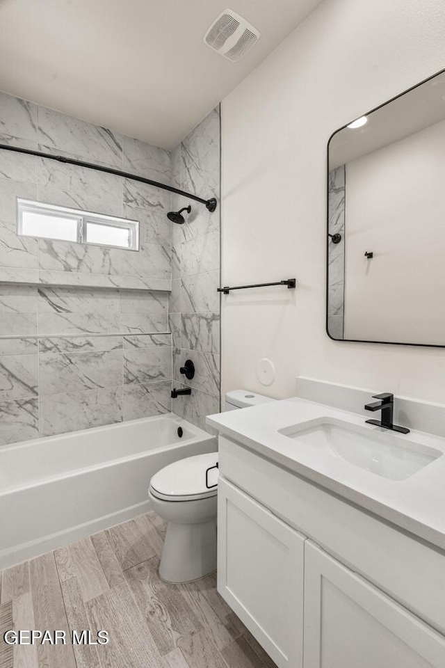 full bathroom featuring shower / tub combination, vanity, toilet, wood finished floors, and visible vents