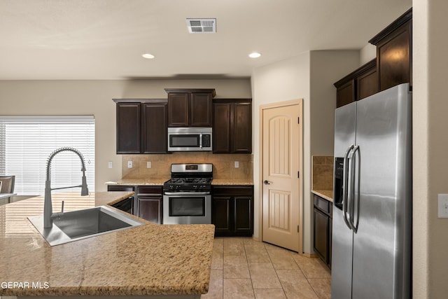 kitchen with visible vents, dark brown cabinetry, a sink, appliances with stainless steel finishes, and backsplash